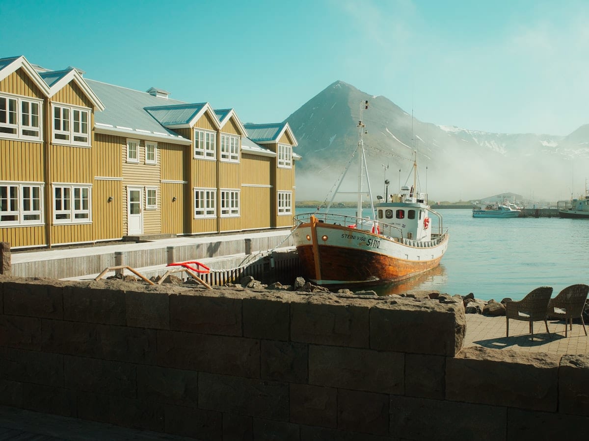 Yellow buildings by a harbor with a boat.