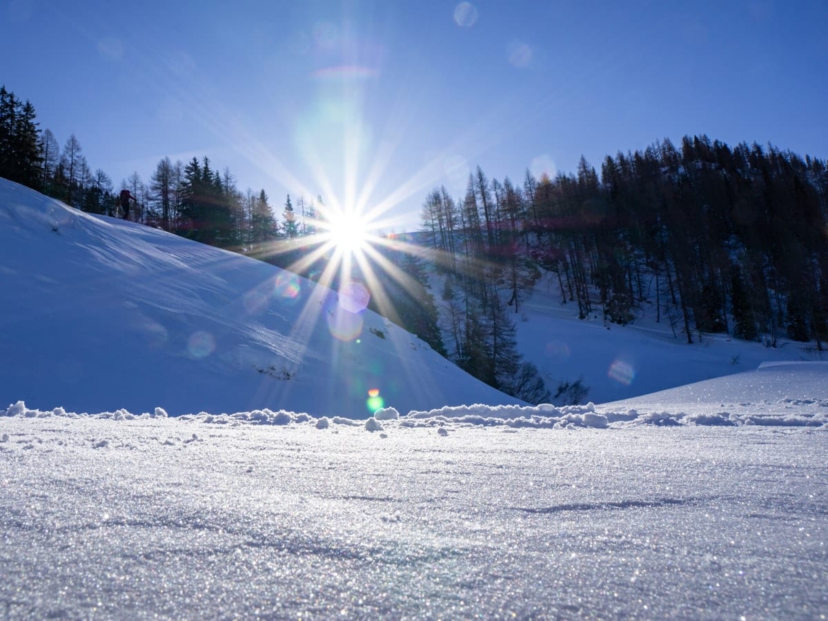 person in green jacket and blue pants standing on snow covered ground during daytime