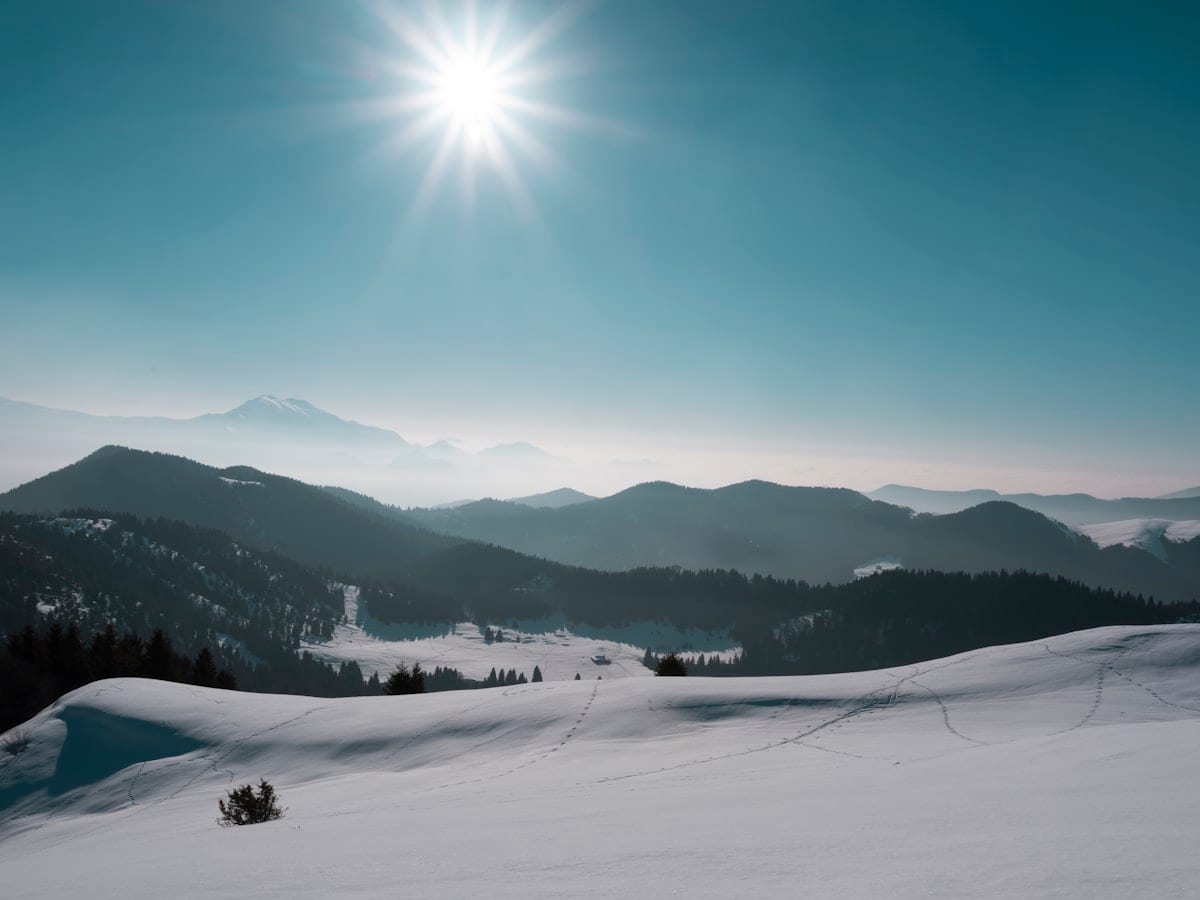 the sun is shining over a snowy mountain
