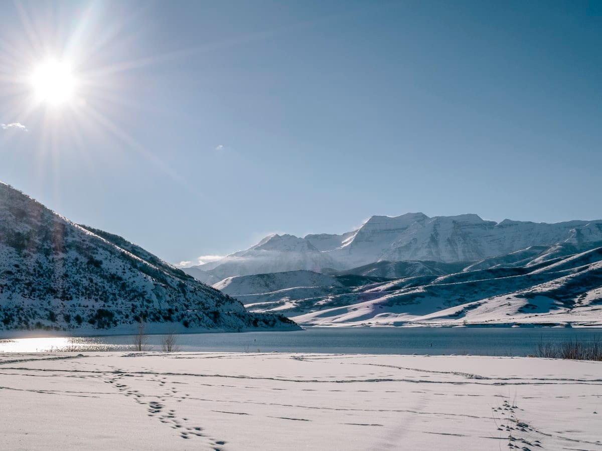 the sun is shining over a snowy mountain range
