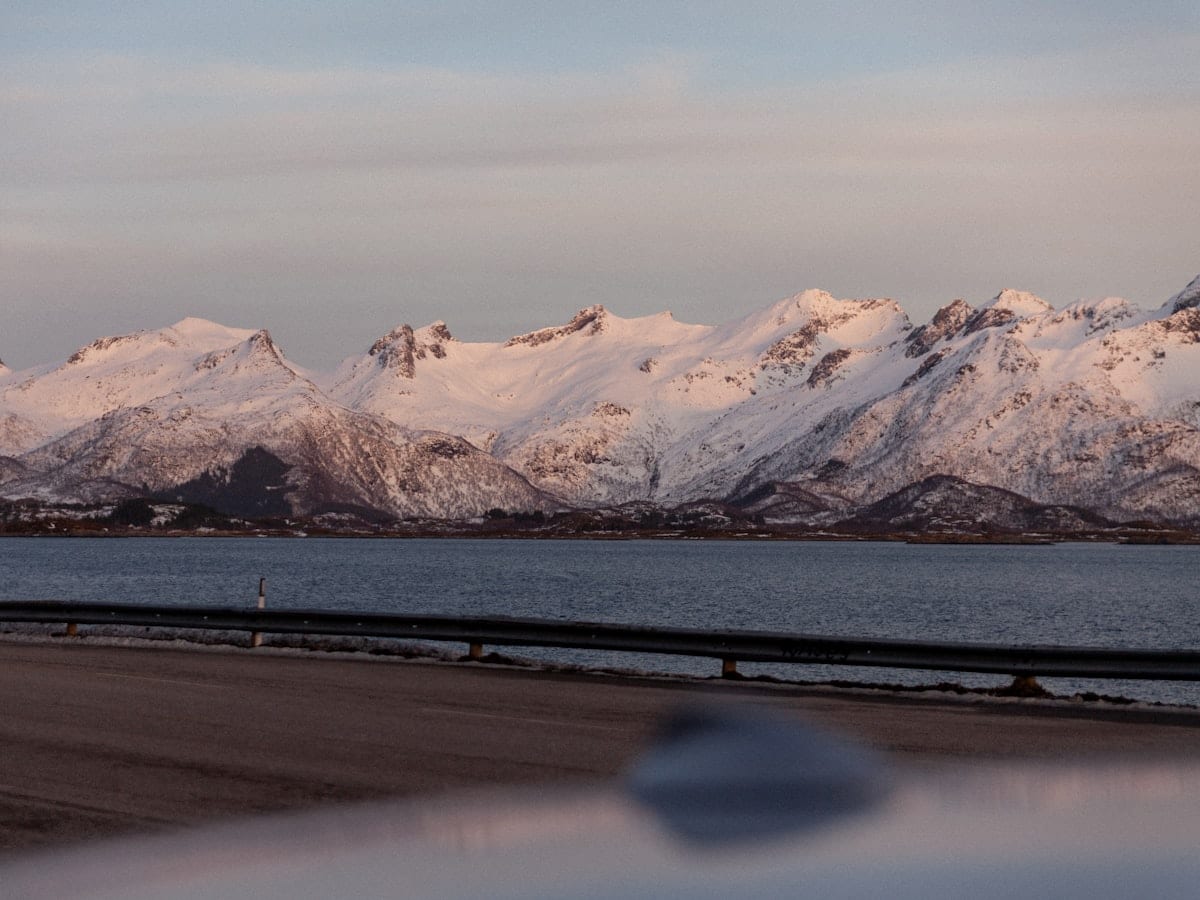 Snow-capped mountains are reflected in the water.