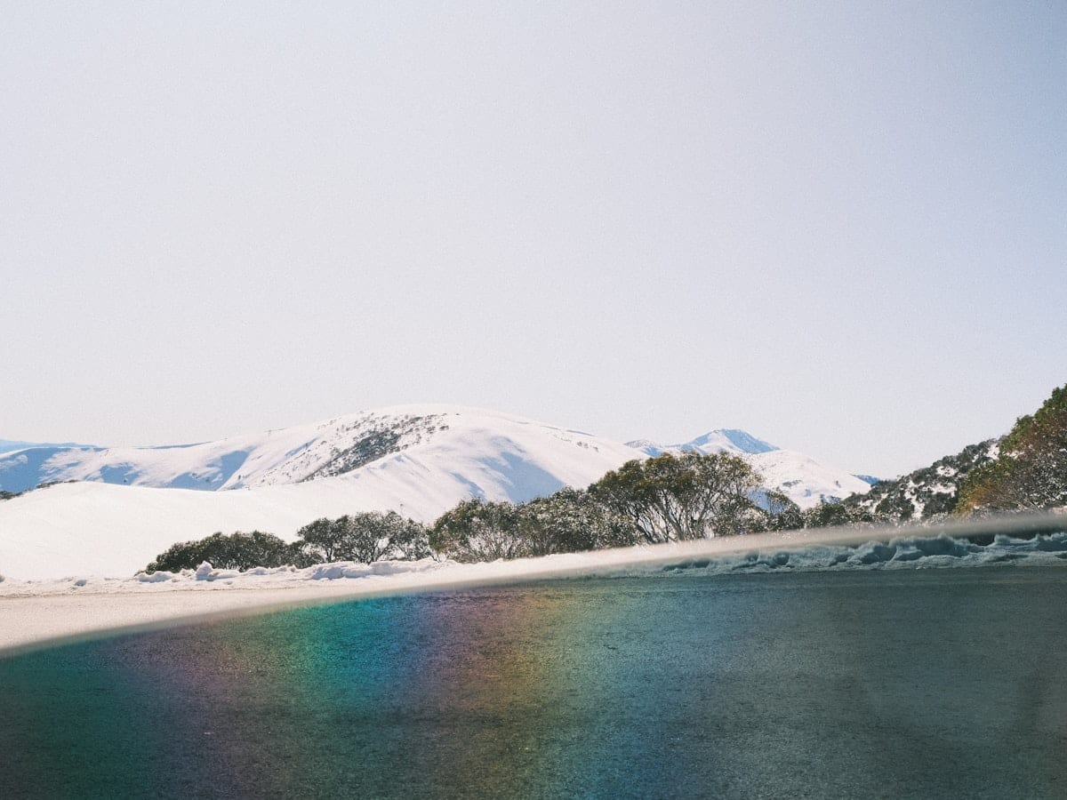 a body of water with snow covered mountains in the background