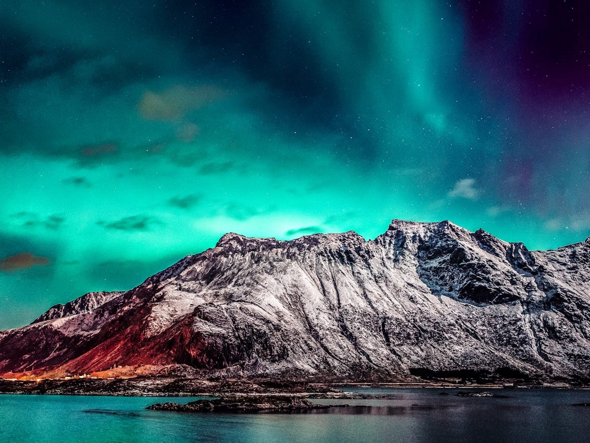 a mountain covered in snow under a green and purple sky