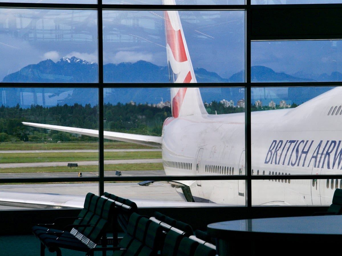 British airways airplane parked at airport with mountains behind