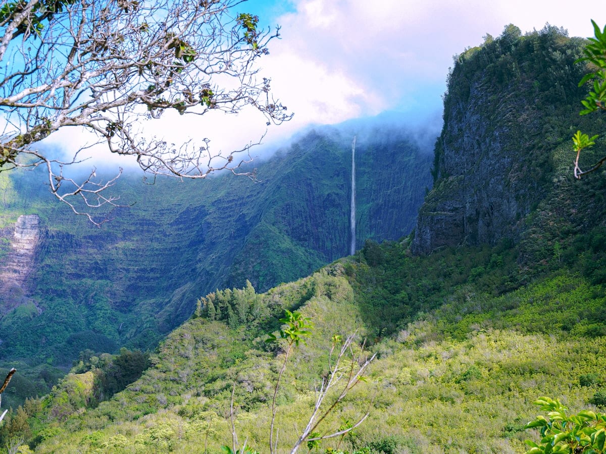 Lush green valley with a tall waterfall cascading down cliffs