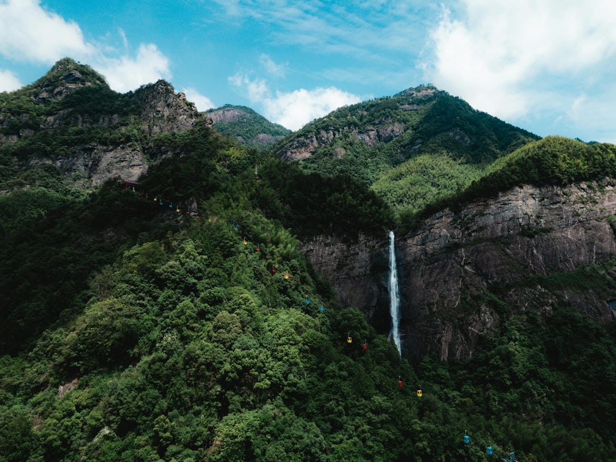 Tall waterfall cascading down a lush green mountain