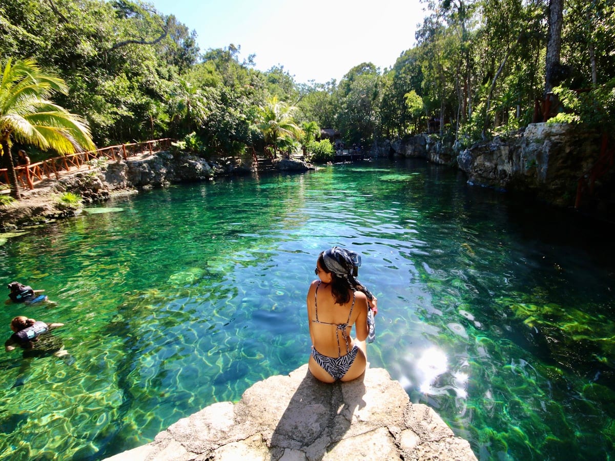 woman in black bikini standing on rock near river during daytime