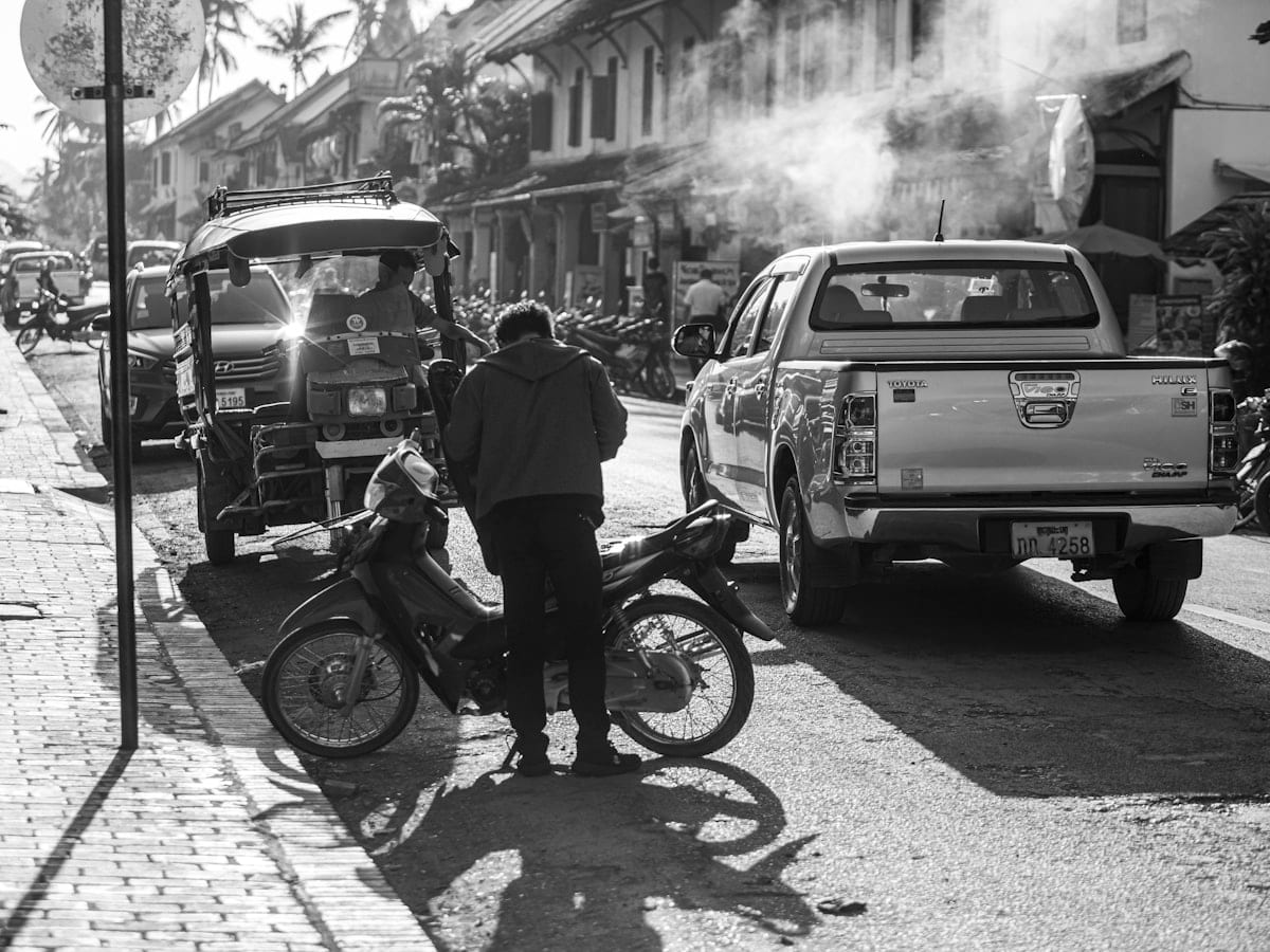 A black and white photo of a man standing next to a motorcycle