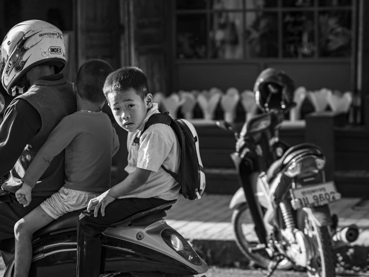 A black and white photo of two boys on a motorcycle