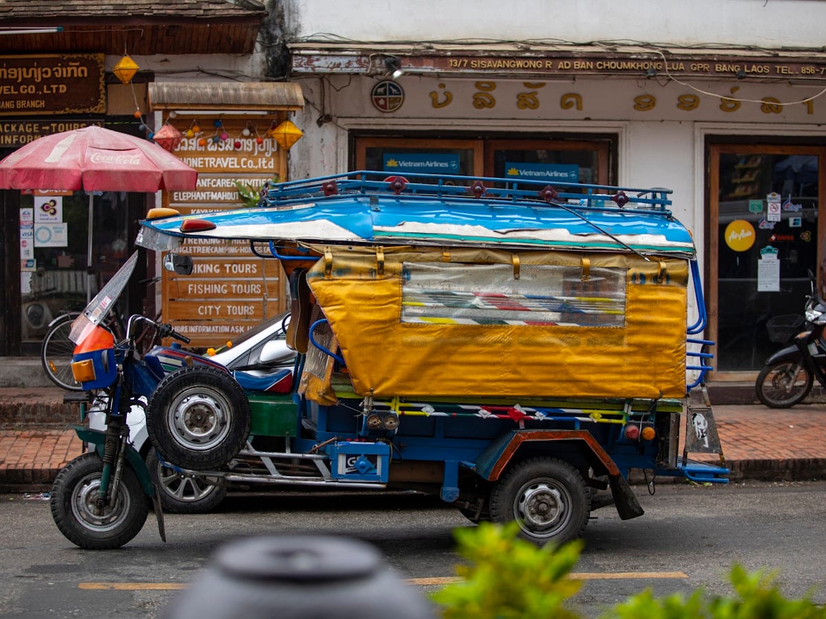 A small yellow and blue truck driving down a street