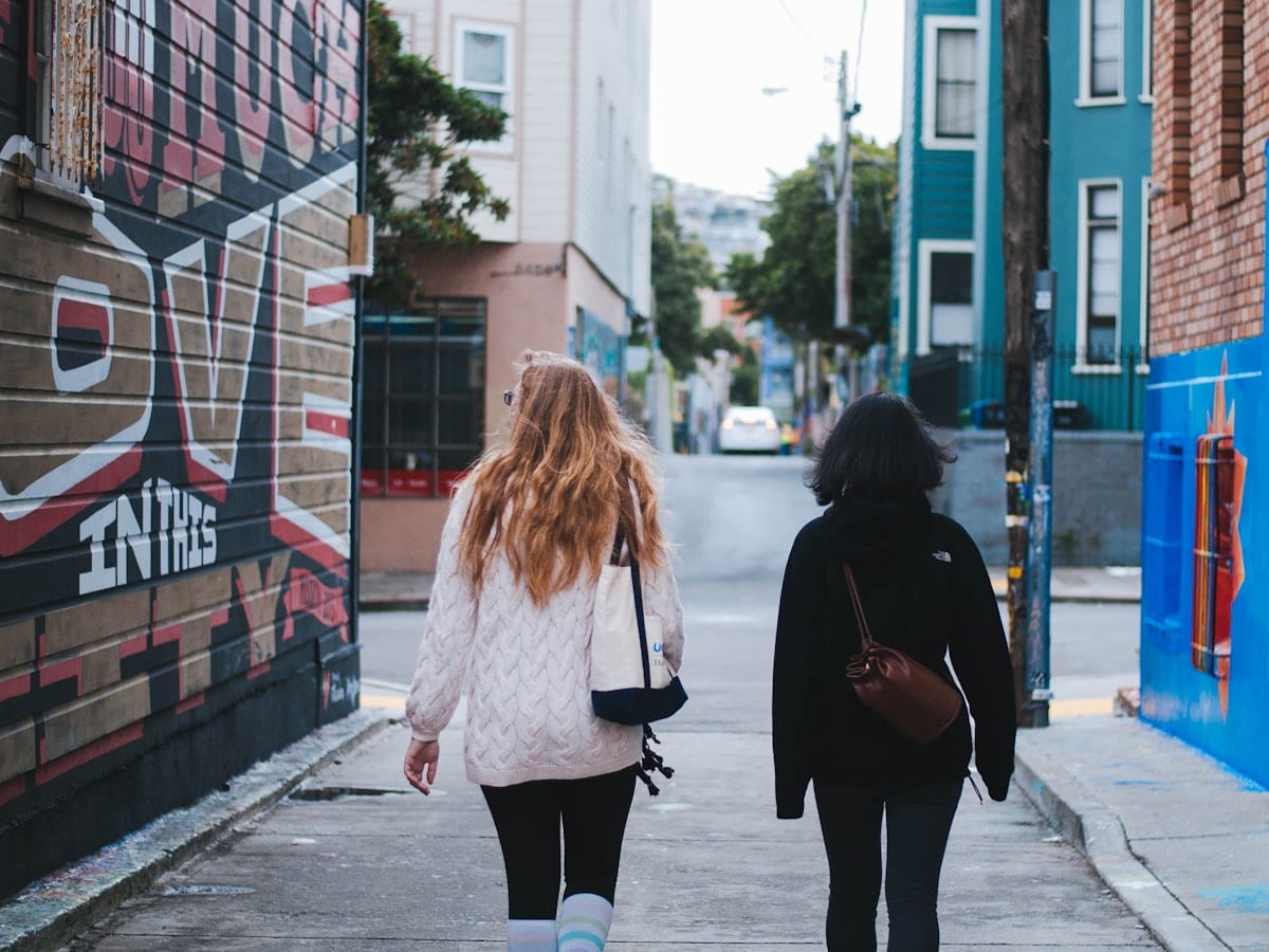 two women in sweaters walking on street