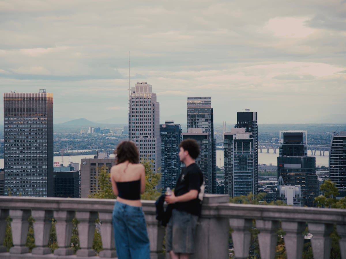 Two people look at a city skyline from a balcony.