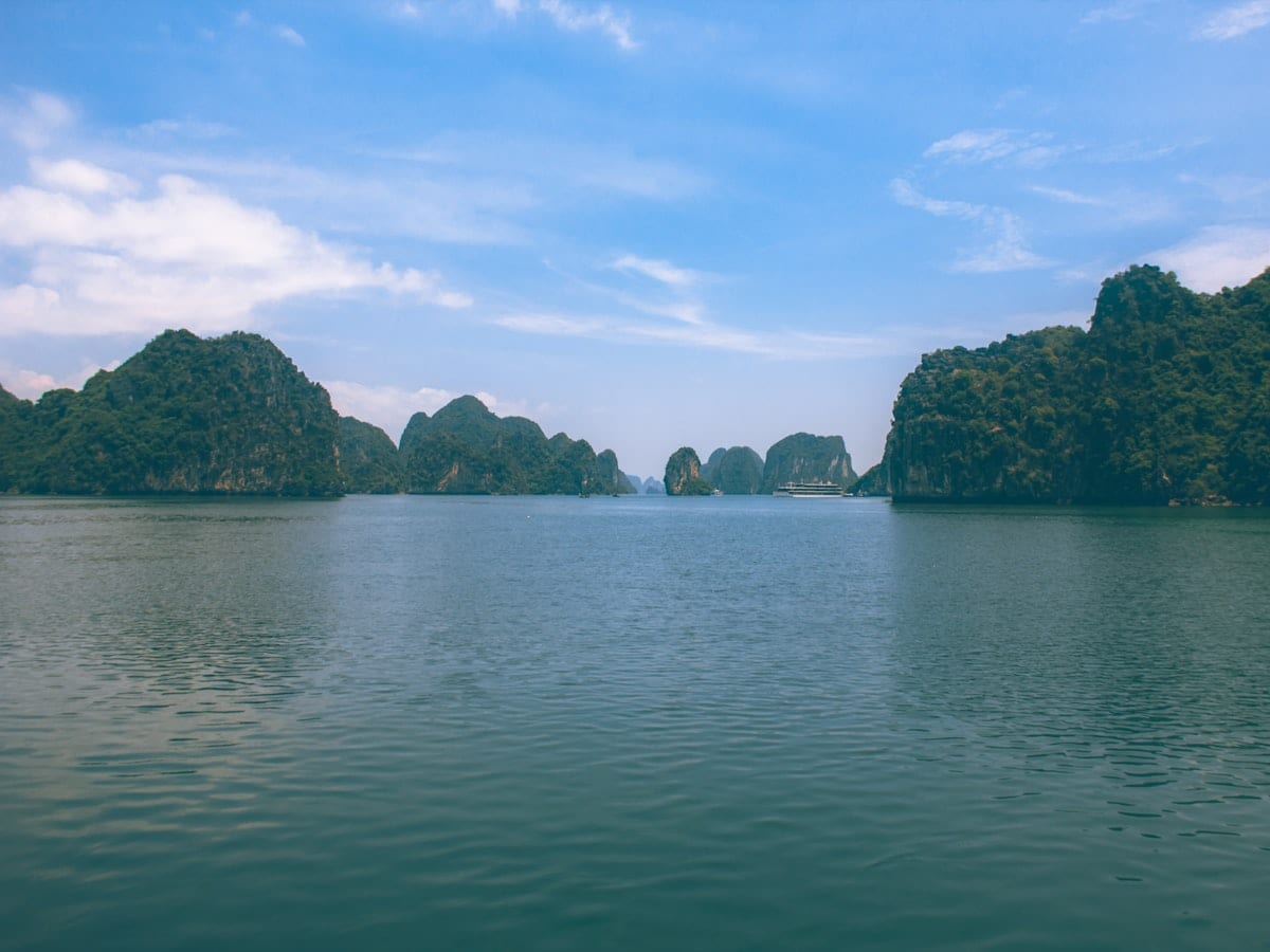 Limestone karsts rise from the ocean under a blue sky.